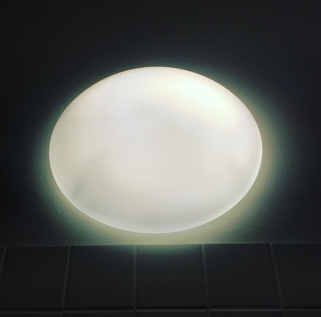 Das Bild zeigt eine dekorative Keramiklampe, dunkle Kacheln, Licht und Schatten. Es symbolisiert Auf und Abs in der Familientherapie in Berlin.